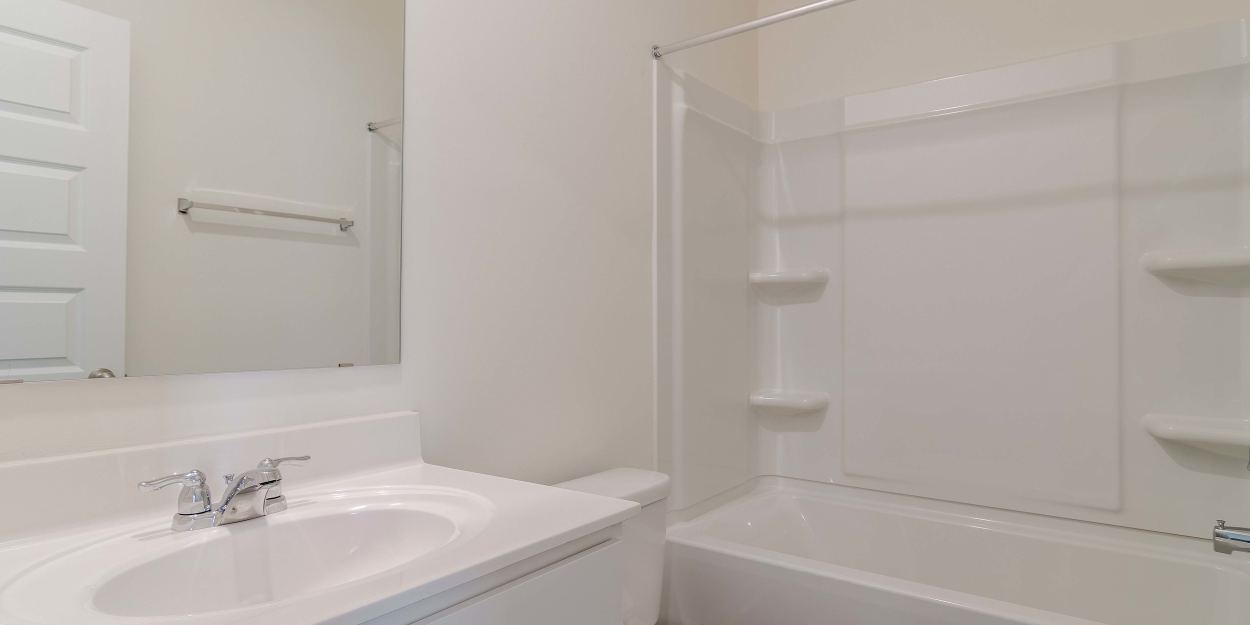 Bright bathroom with white vanity, toilet and tub-shower combo The Lakes at Statham in Statham, Georgia