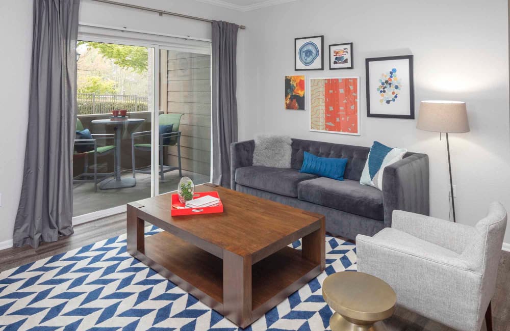 A fully furnished unit with a rug on top of hardwood floors, a couch, love seat and coffee table at The Grove at Orenco Station in Hillsboro, Oregon