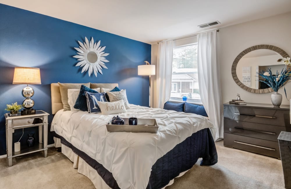 Model bedroom with plush carpeting and a blue accent wall at Avery Park Apartment Homes in Silver Spring, Maryland