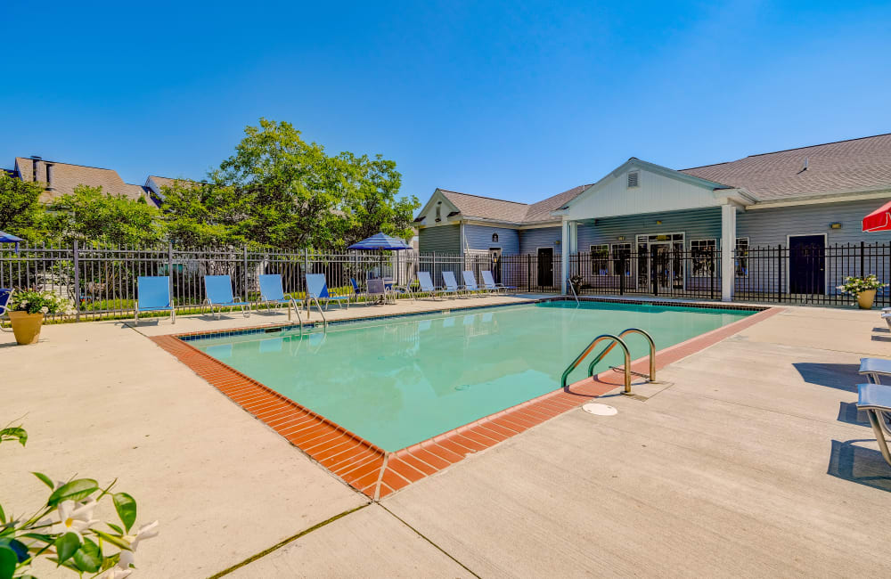 Swimming pool with chairs and umbrellas on the pool deck at Fox Run Apartments & Townhomes in Bear, Delaware