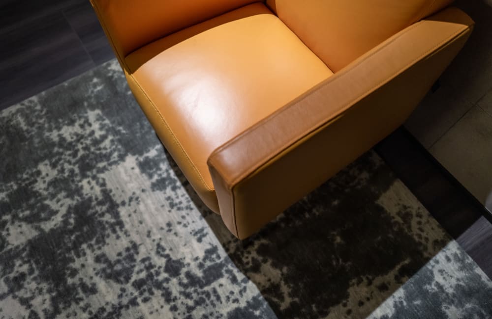 A leather armchair on a dark rug in apartment's living area at Mariposa at Ella Boulevard in Houston, Texas