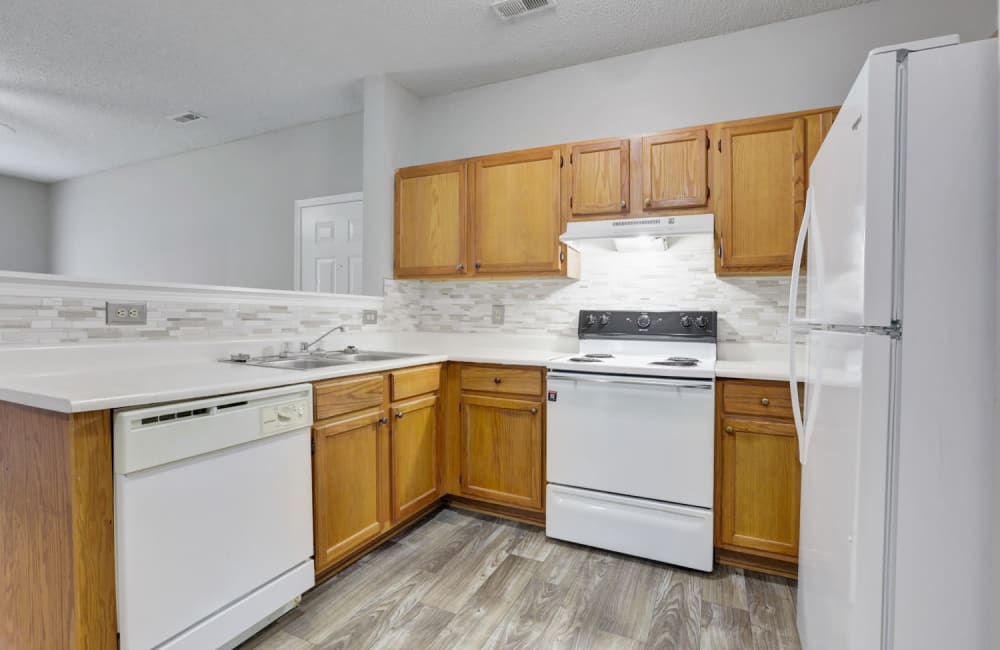 Kitchen with white appliances and wood cabinets at Clemmons Station Apartment Homes in Clemmons, North Carolina