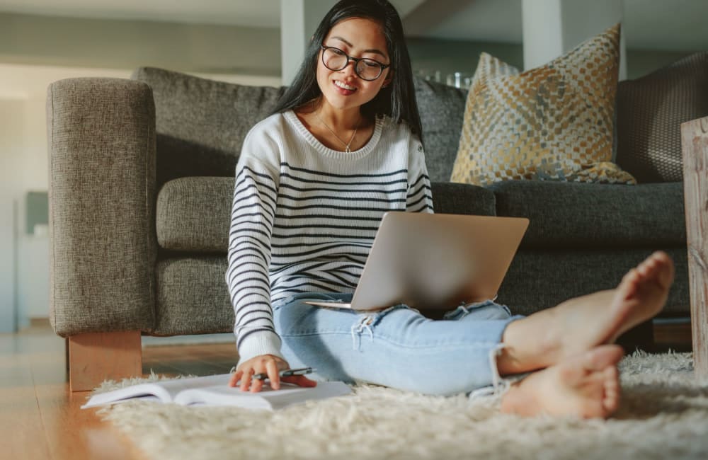 Resident sitting on floor with laptop at Coventry Commons in Louisville, Kentucky
