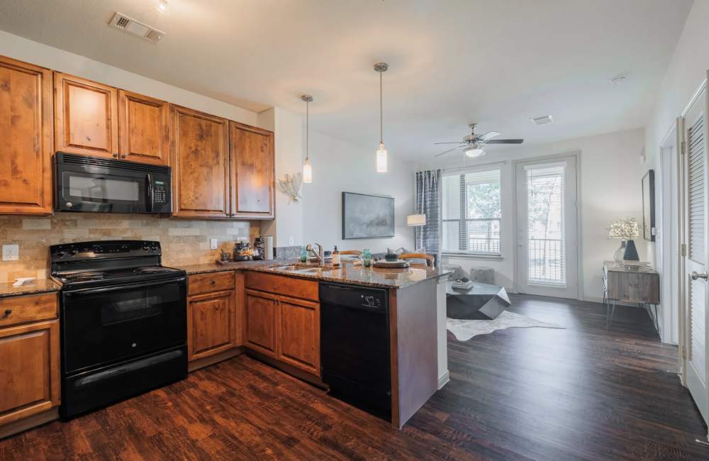 Wood-style flooring in an apartment kitchen and living room at The Pines at Woodcreek in Humble, Texas