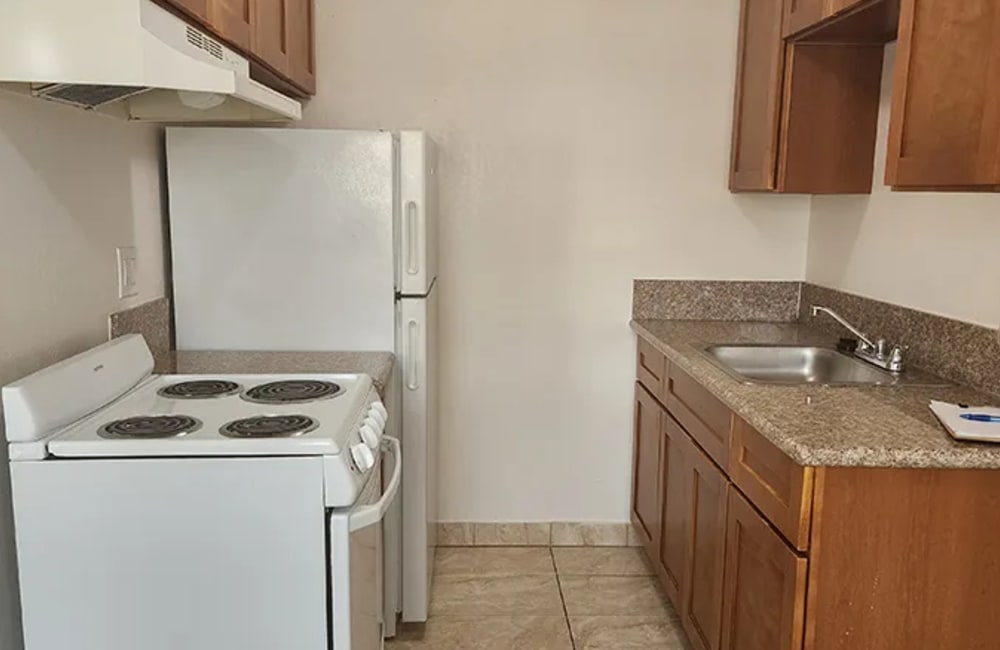 Modern kitchen with sleek granite countertops and a refrigerator at Villas At Millbrook in Fresno, California