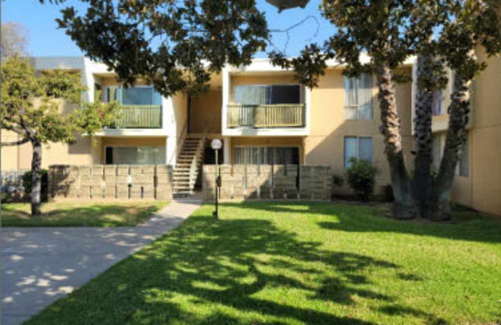 Exterior view of an apartment nestled amidst lush green grass and trees at Lexington Green in El Cajon, California