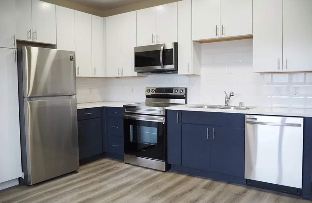 Kitchen with appliances including refrigerator, microwave, oven, and cupboard storage at The Atrium at Victorian Square in Sparks, Nevada