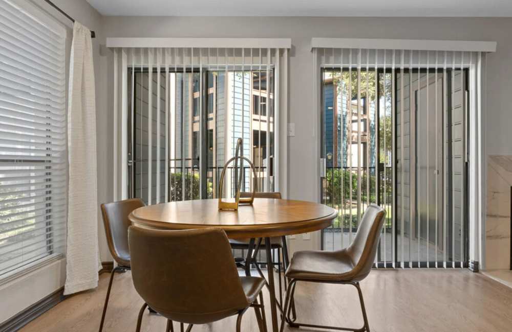 Dining area with wooden table, chairs and large windows at Hill At Woodway in San Antonio, Texas