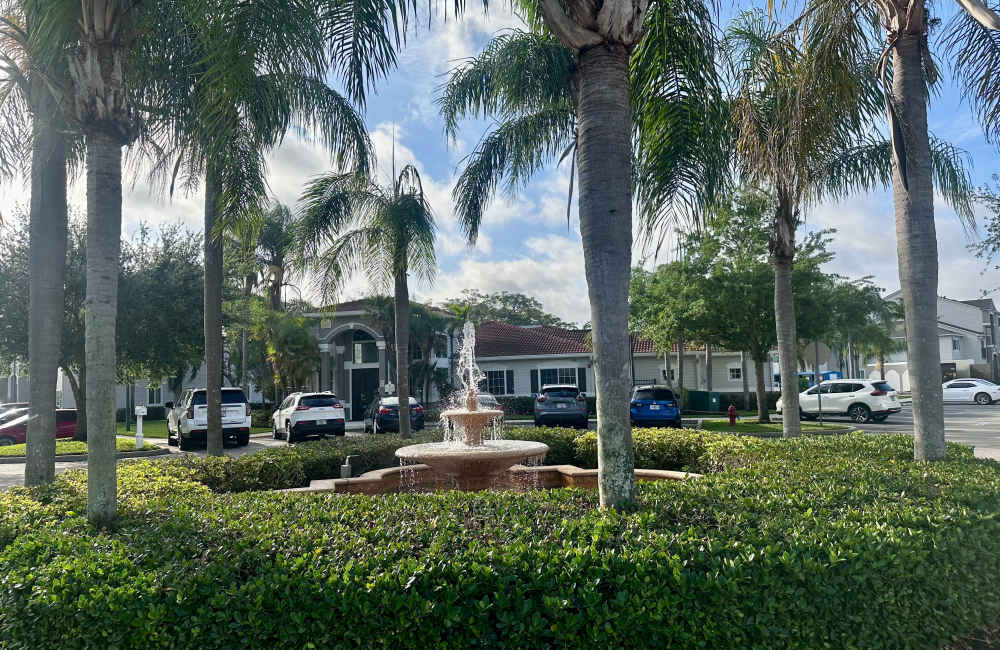 A water fountain surrounded by bushes and trees at Hawk's Landing in Fort Myers, Florida