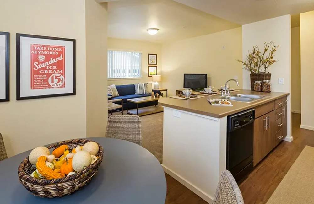 Comfortable kitchen with a dishwasher and living room in the background at Copper River in Spokane, Washington
