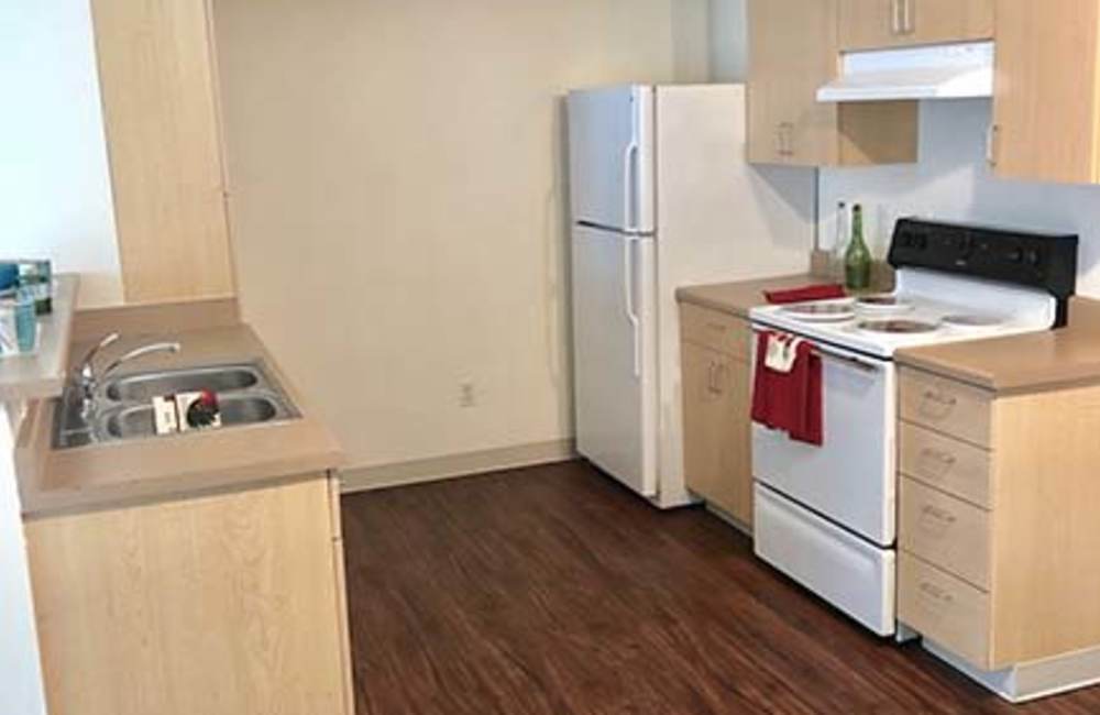 Kitchen with island and bar stools, refrigerator, stove, and wood cabinetry at Heron Creek Apartments in Moses Lake, Washington