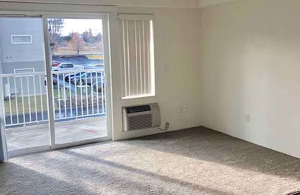 Spacious living room with sliding glass doors for patio access at Heron Creek Apartments in Moses Lake, Washington
