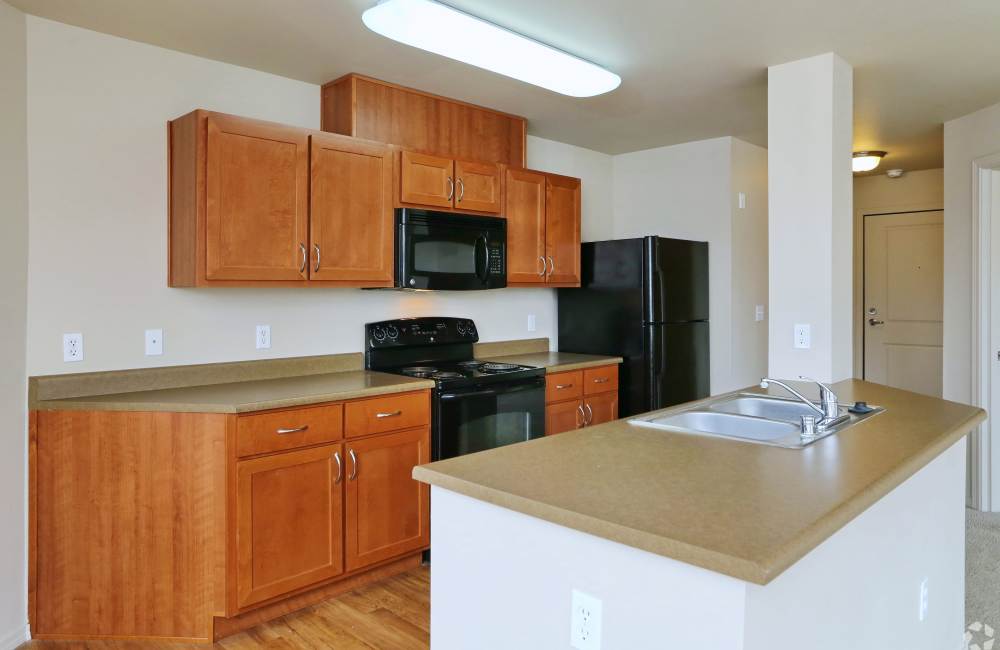 Spacious island kitchen, oven, and wood cabinetry at The Blakely in Shoreline, Washington