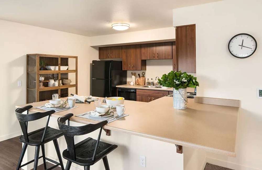 Kitchen with island and bar stools, refrigerator, stove, and wood cabinetry at Traditions at Federal Way in Federal Way, Washington