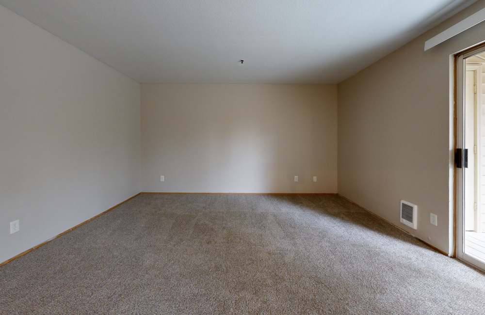 Spacious bedroom with carpeted floor and a glass sliding door leading to a balcony at Heron Hills Apartment Homes in Gresham, Oregon