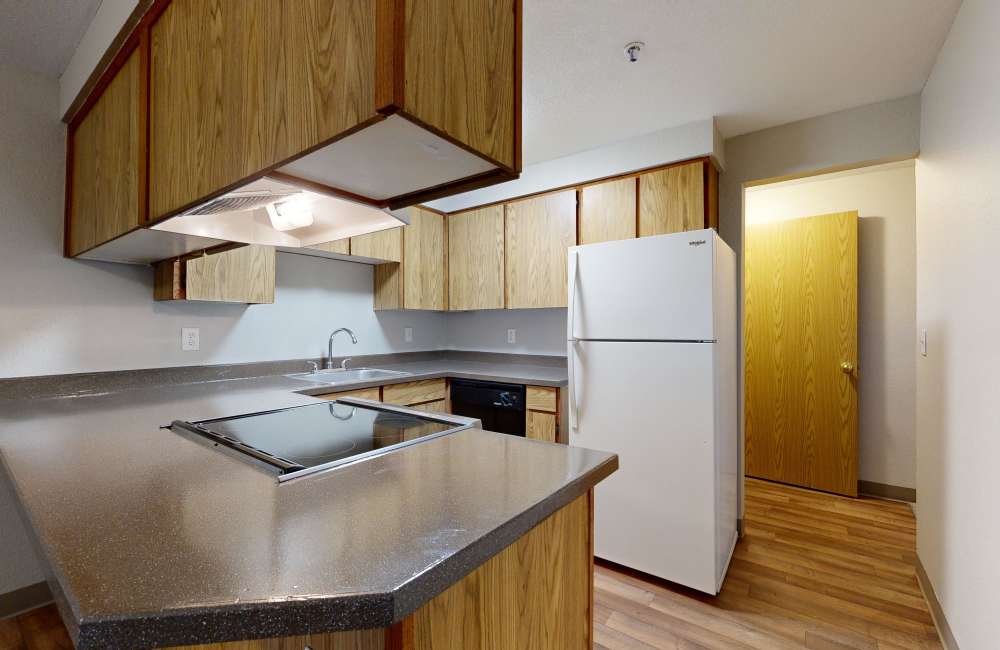 Kitchen with granite countertops, refrigerator at Heron Hills Apartment Homes in Gresham, Oregon
