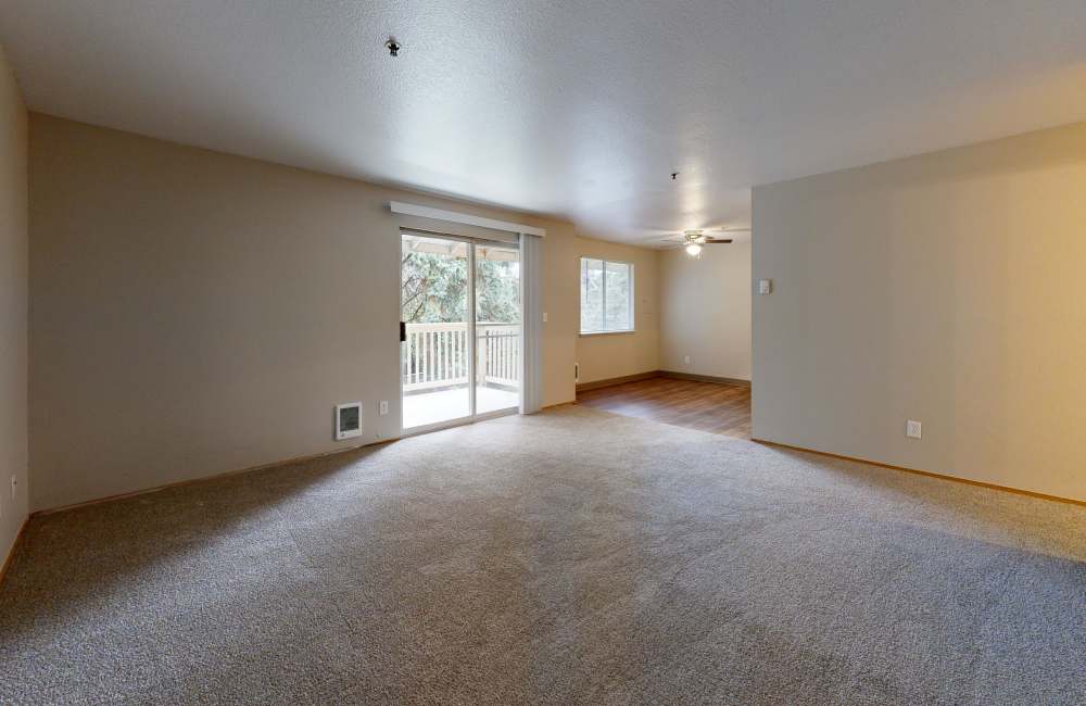 A spacious bedroom with large windows, and a balcony at Heron Hills Apartment Homes in Gresham, Oregon