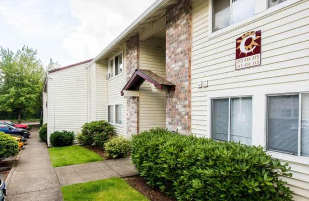 Apartment building with brick accents and shrubs in front at Heron Hills Apartment Homes in Gresham, Oregon