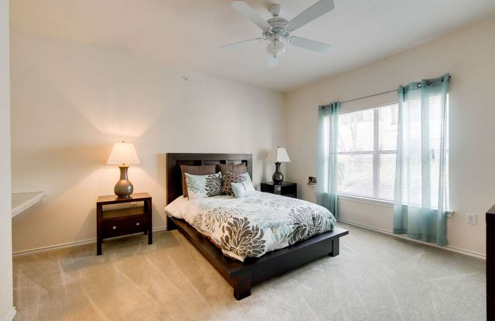 Spacious bedroom with large comfortable bed and ceiling fan at The Forum at Grand Prairie in Grand Prairie, Texas, 