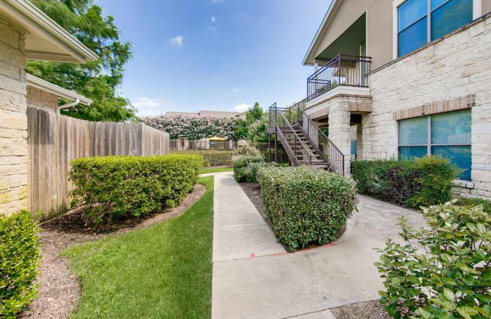 View of exterior of apartments and green lawn at The Forum at Grand Prairie in Grand Prairie, Texas, 