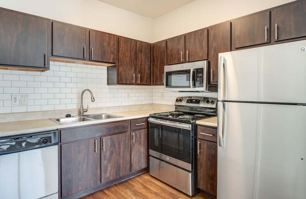 Fully equipped kitchen with granite countertops, stainless steel appliances like a refrigerator and drawer microwave at The Forum at Grand Prairie in Grand Prairie, Texas, 