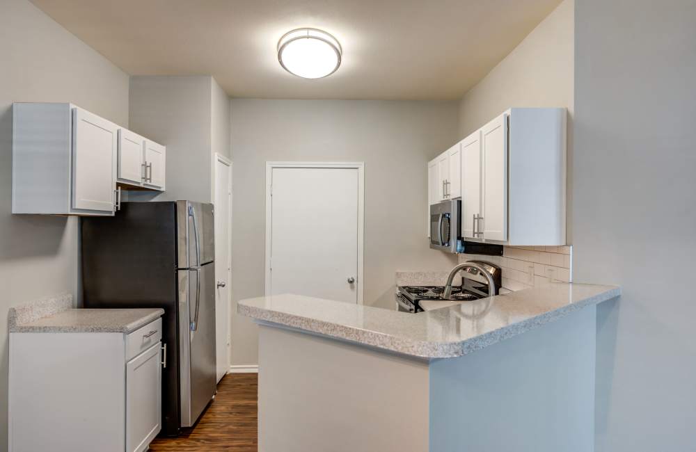 Spacious island kitchen with hard-wood style flooring at The Forum at Grand Prairie in Grand Prairie, Texas, 