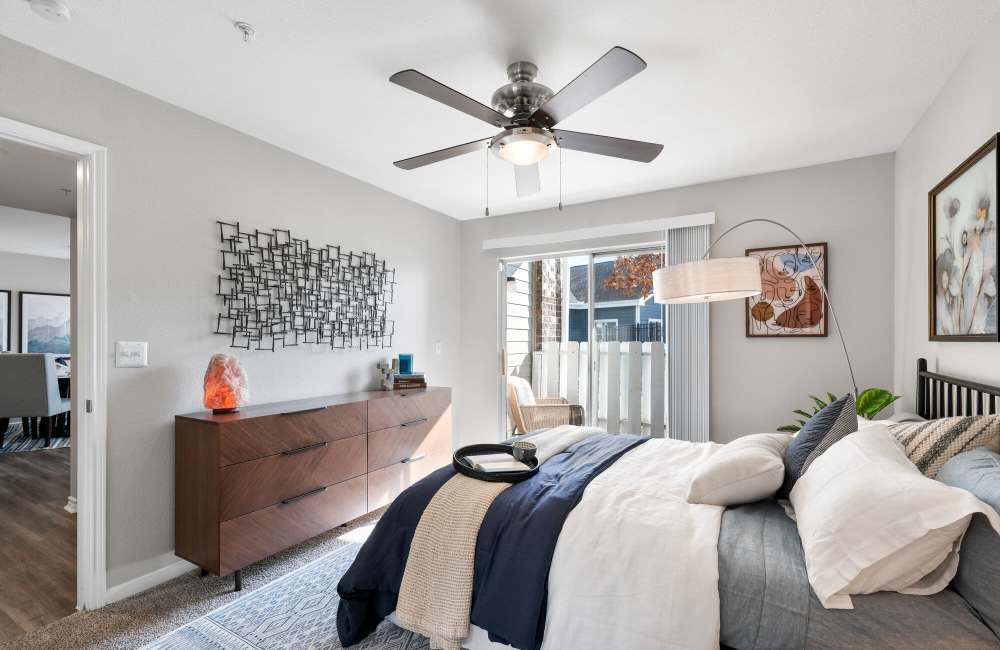 Well-lit and spacious bedroom with ceiling fan and carpet at Park At Woodmoor Apartments in Shenandoah, Texas, 