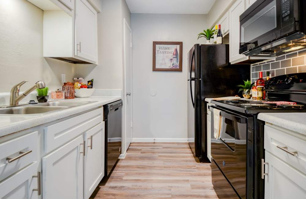 Modern kitchen with wood-style flooring and black appliances at South Shore Coastal Living in Corpus Christi, Texas
