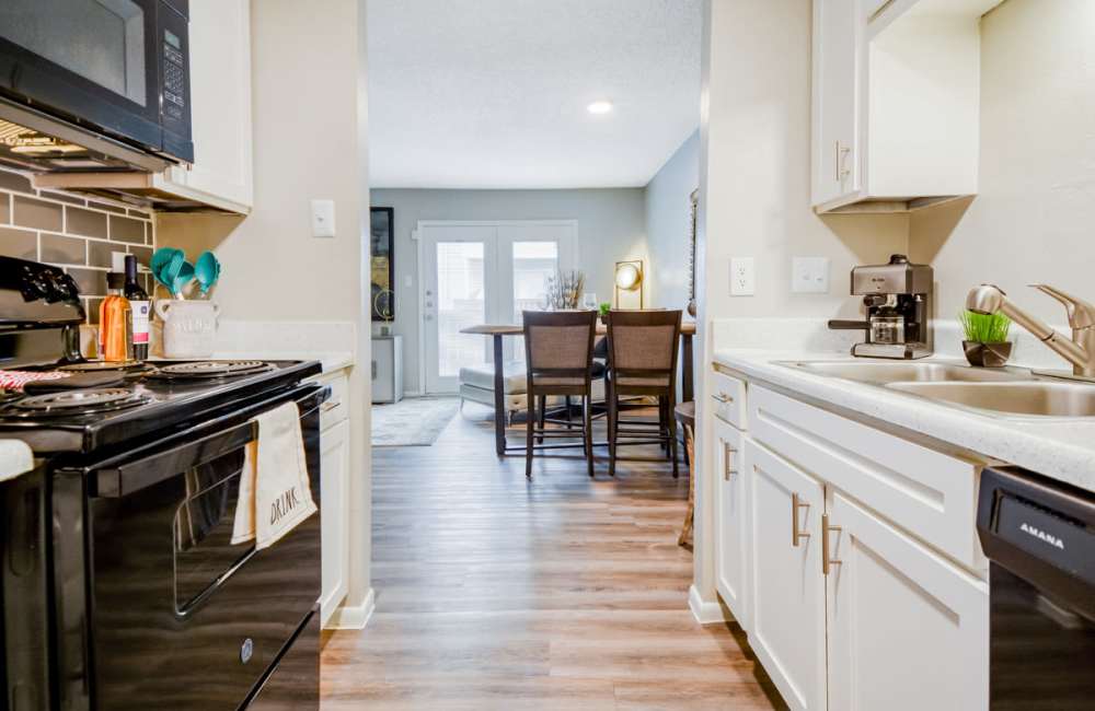 Cozy kitchen with black appliances including refrigerator, dishwasher and white cabinetry at South Shore Coastal Living in Corpus Christi, Texas, 