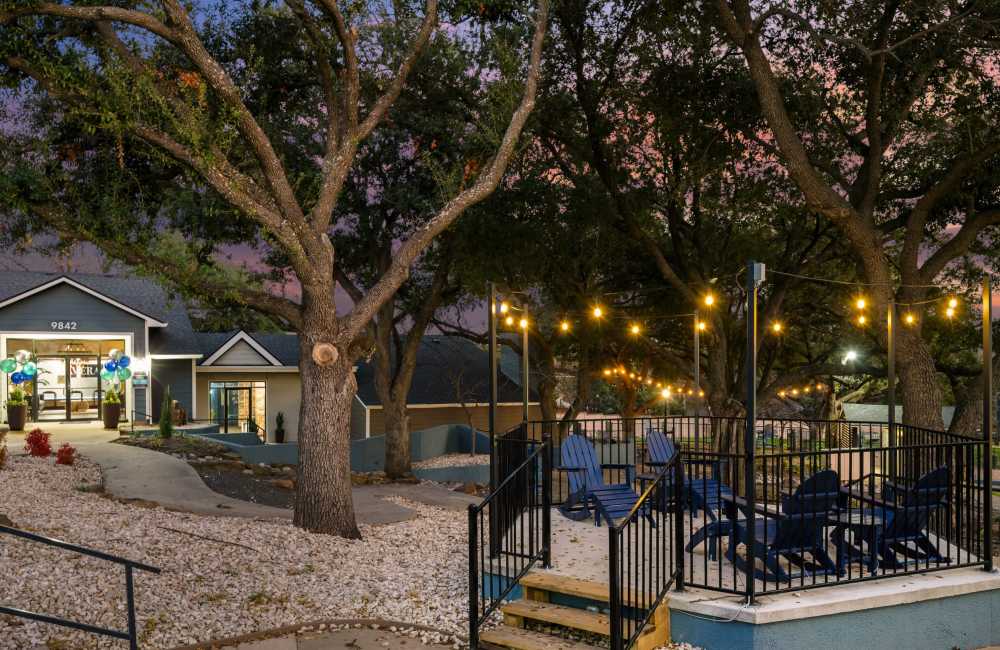 Community outdoor seating area at night with cafe lights and comfy adirondak seating at Lavera At Lake Highlands in Dallas, Texas