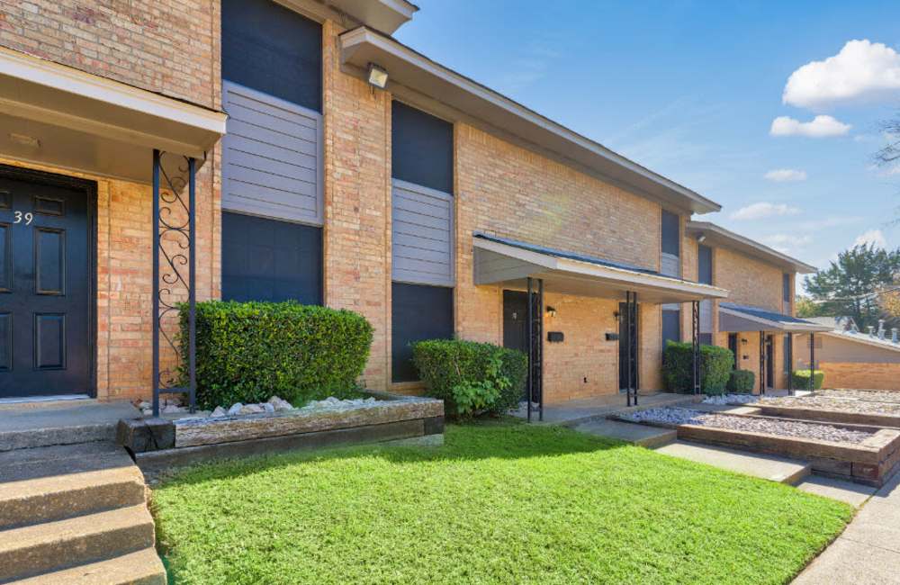 View of exterior of apartments and green lawn at Troup Townhomes in Troup, Texas