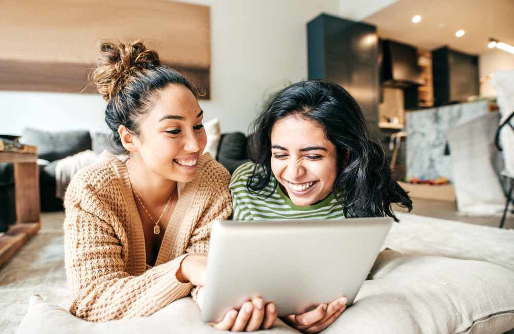 Happy friends working on iPad at Boomer Creek Apartments in Stillwater, Oklahoma