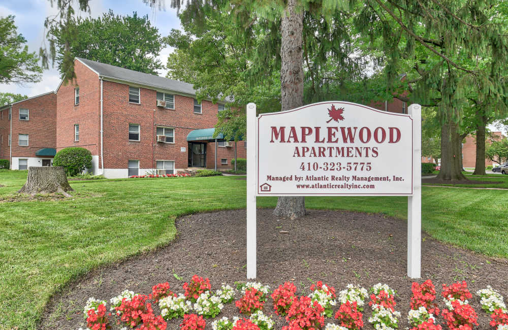 Exterior shot of apartments with property signage board at Maplewood Apartments in Baltimore, Maryland