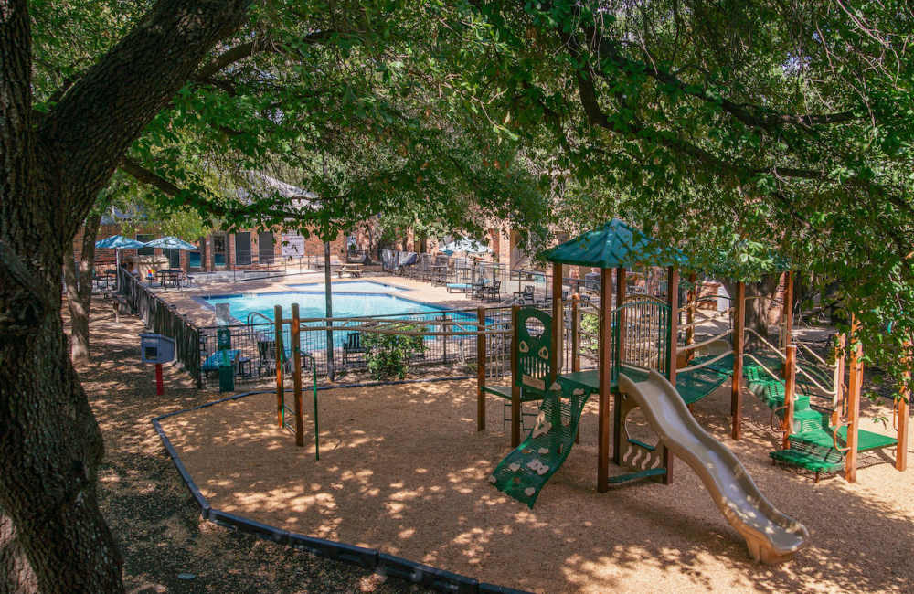 View of swimming pool with playground at Sierra Vista Apartments in Austin, Texas