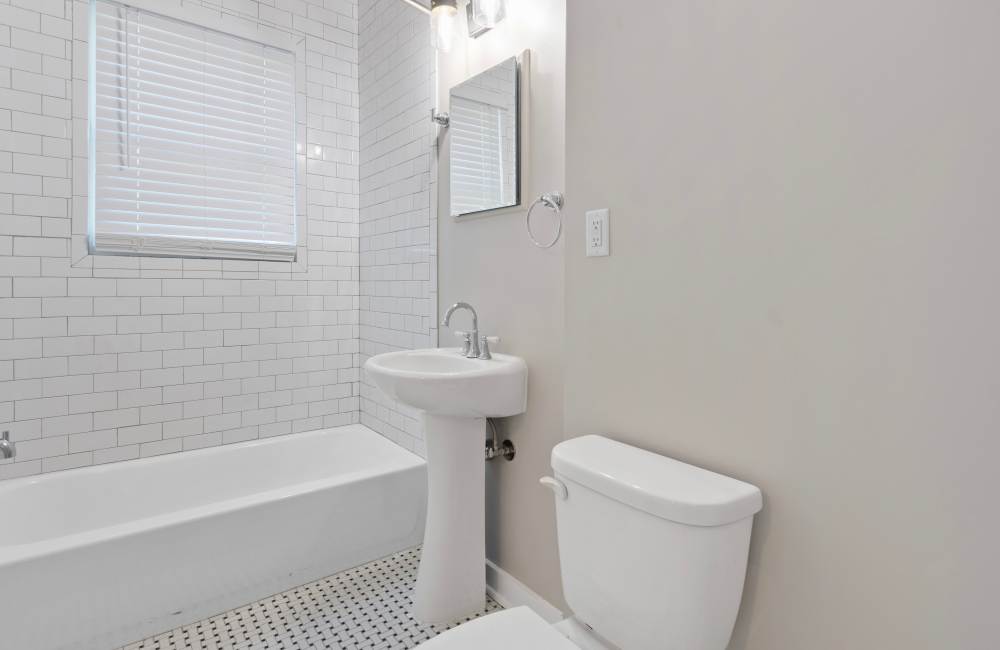 Bathroom with pedestrian sink, commode and tub at The Alma in Memphis, Tennessee