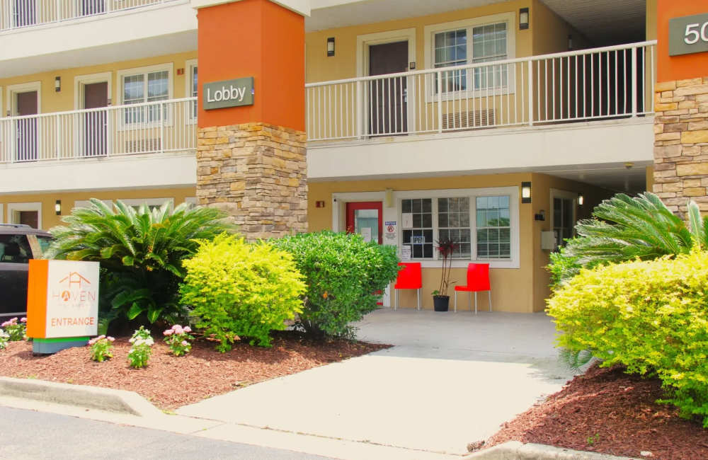 Gated entrance with vibrant landscaping and seating area near lobby entrance at Haven at Arco in North Charleston, South Carolina
