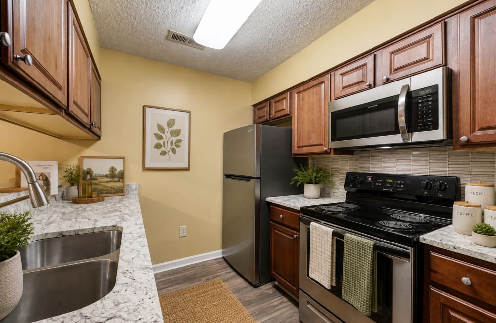 Kitchen with wood cabinets, black appliances and marble-look counters at Chason Ridge Apartment Homes in Fayetteville, North Carolina