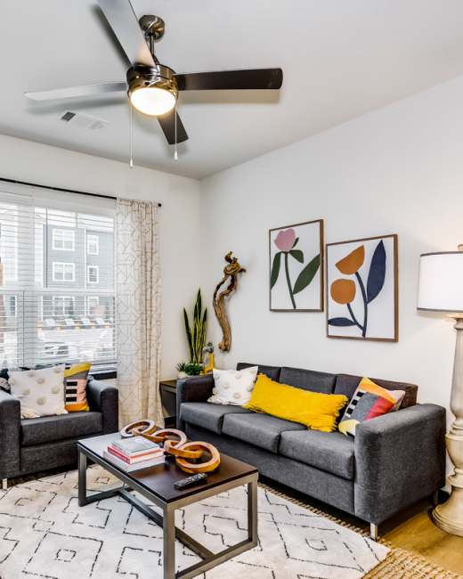 Bright trendy living room with hardwood floors and ceiling fan at Altitude at Wichita in Wichita, Kansas