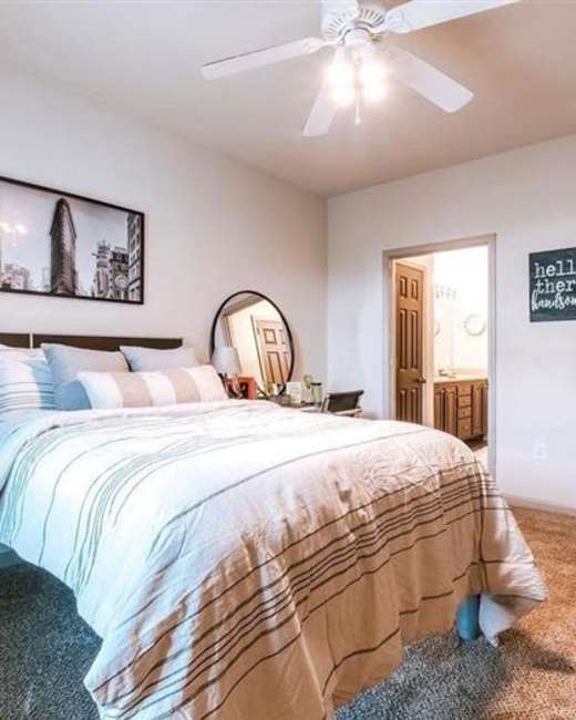 Carpeted apartment bedroom with ceiling fan at The Landing at Fayetteville in Fayetteville, Arkansas