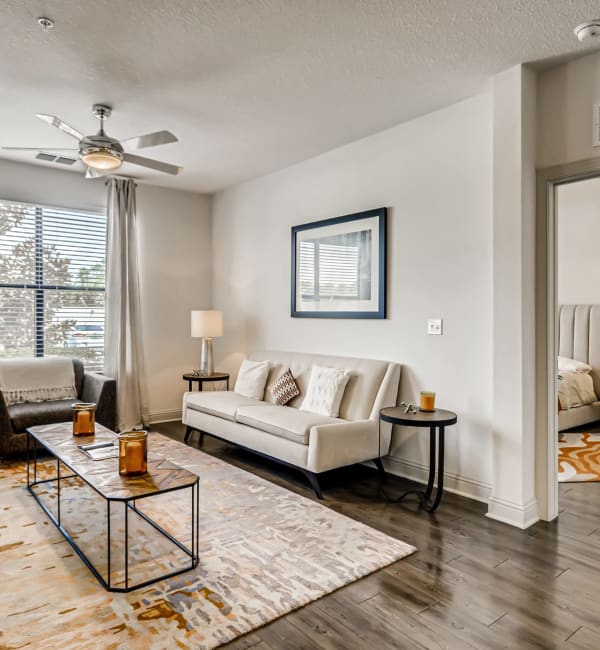 A furnished apartment living room with wood flooring and a ceiling fan at EOS in Orlando, Florida