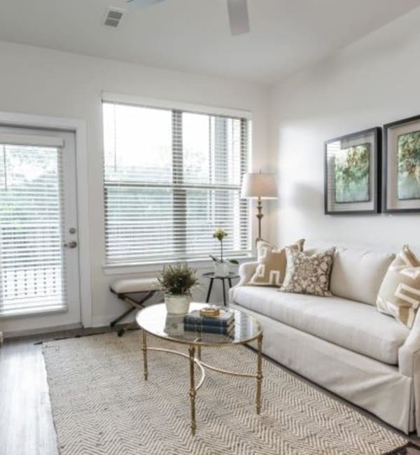 An apartment living room with a couch and a glass coffee table at Retreat at Fairhope Village in Fairhope, Alabama