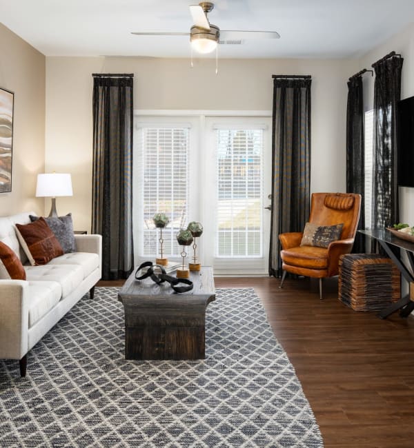 An apartment living room with a couch and a large windows at The Alexandria in Madison, Alabama