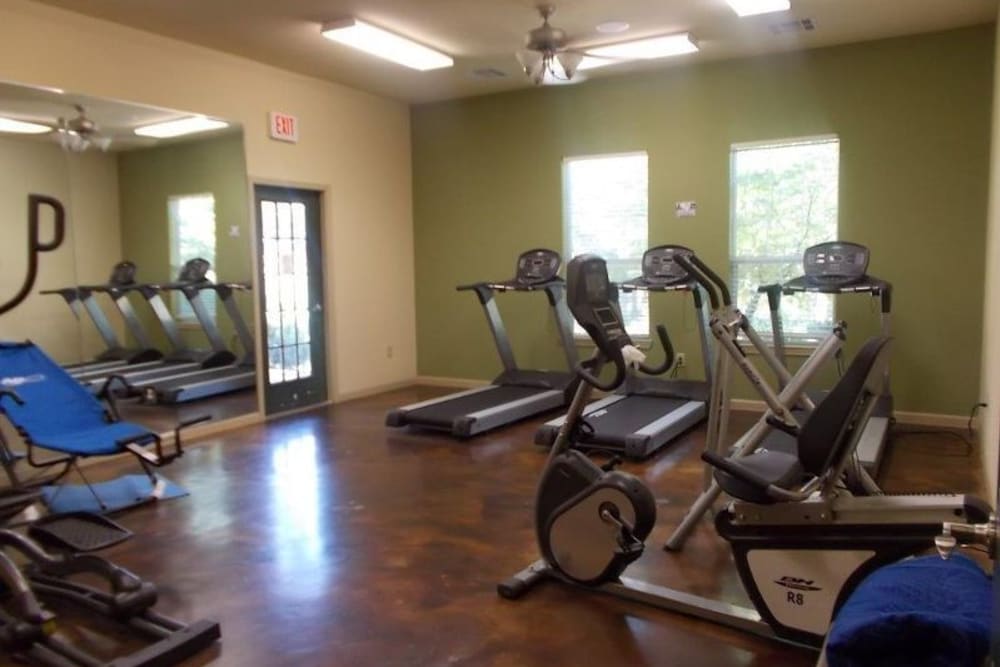 A fitness center with individual workout stations at Woodside Manor in Conroe, Texas