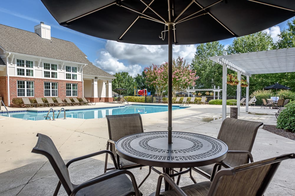 Patio table with an umbrella by the pool at Falls Creek Apartments & Townhomes in Raleigh, NC