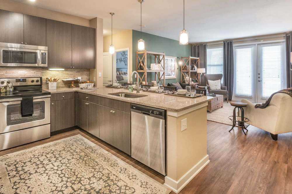 Spacious island kitchen with dishwasher and wood cabinetry at The Abbey at Spring Town Center in Spring, Texas