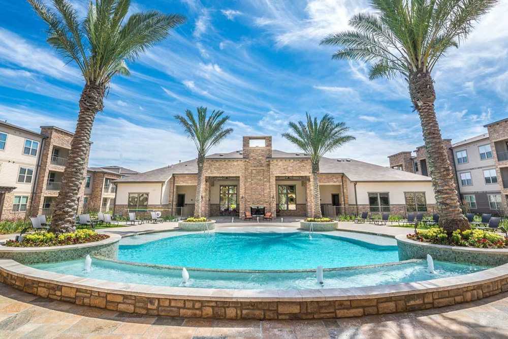 Wide view of swimming pool with club house at The Abbey at Spring Town Center in Spring, Texas