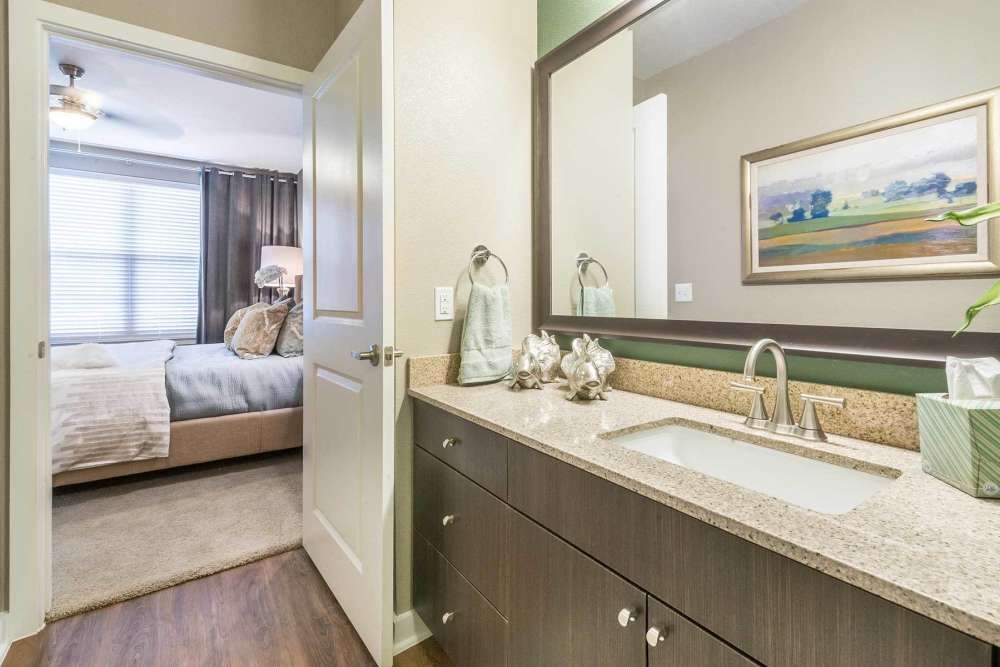 Spacious bedroom with connecting bathroom and hardwood flooring at The Abbey at Spring Town Center in Spring, Texas