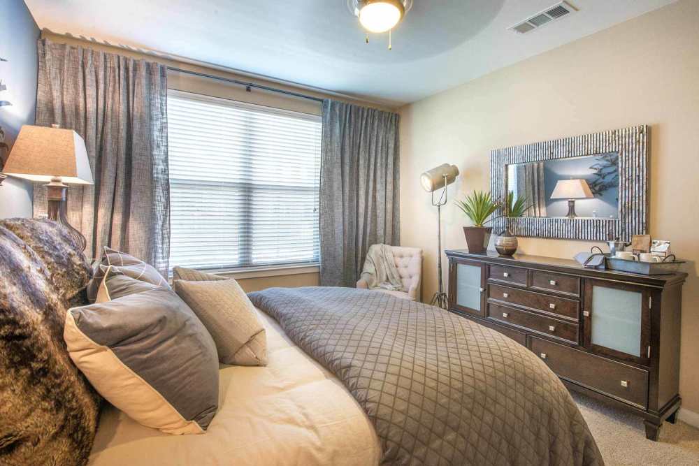 Bright bedroom with large comfortable bed, desk, and large window at The Abbey at Spring Town Center in Spring, Texas