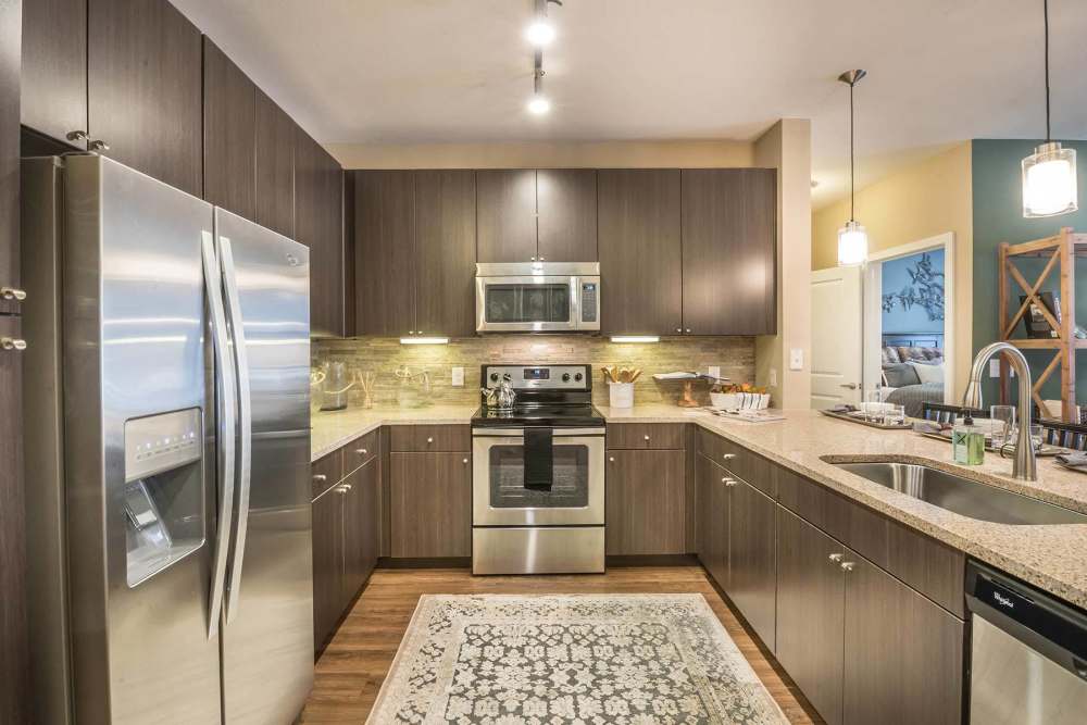Kitchen island with waterfall faucet, dishwasher, pendant lighting and hard-wood flooring at