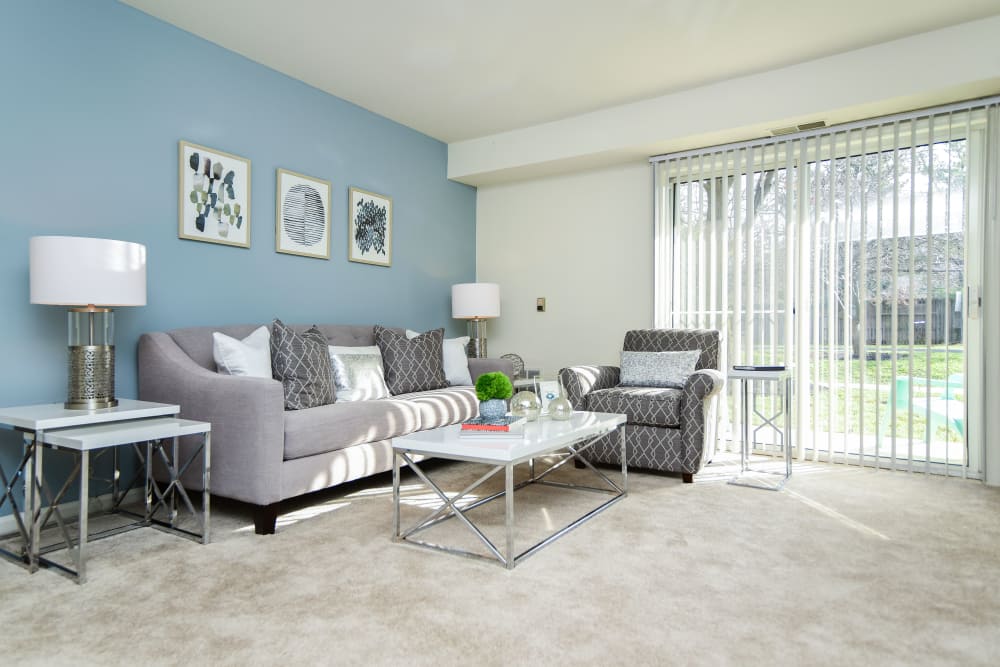 Carpeted living room with sliding door access to a private patio at Abrams Run Apartment Homes in King of Prussia, Pennsylvania